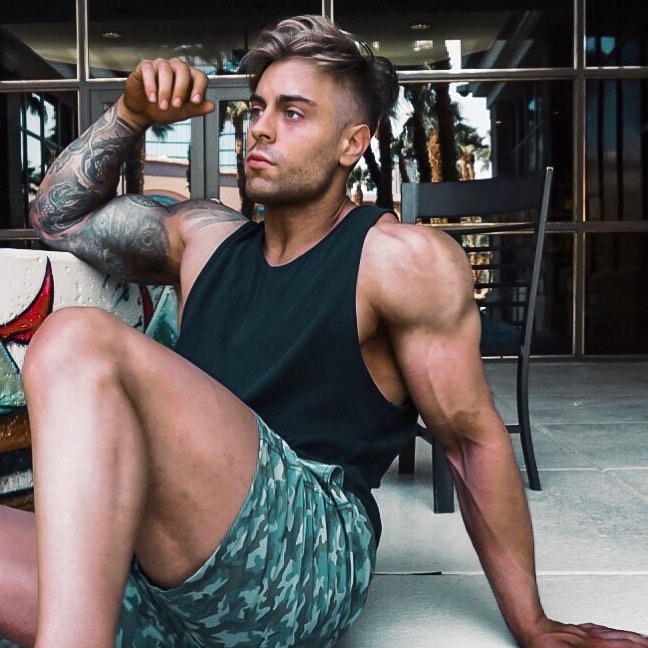 Andre Habowsky sitting down on a floor in the gym, looking fit and muscular
