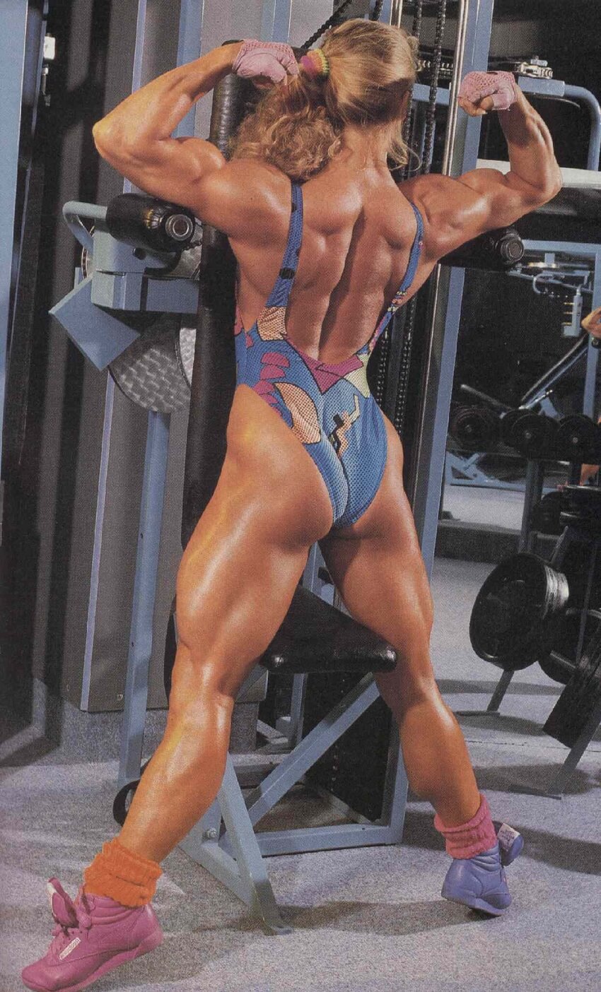 Anja Langer flexing her back and glutes for the photo in the gym