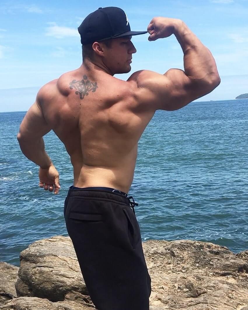 Caique Meirelles flexing biceps shirtless by the sea