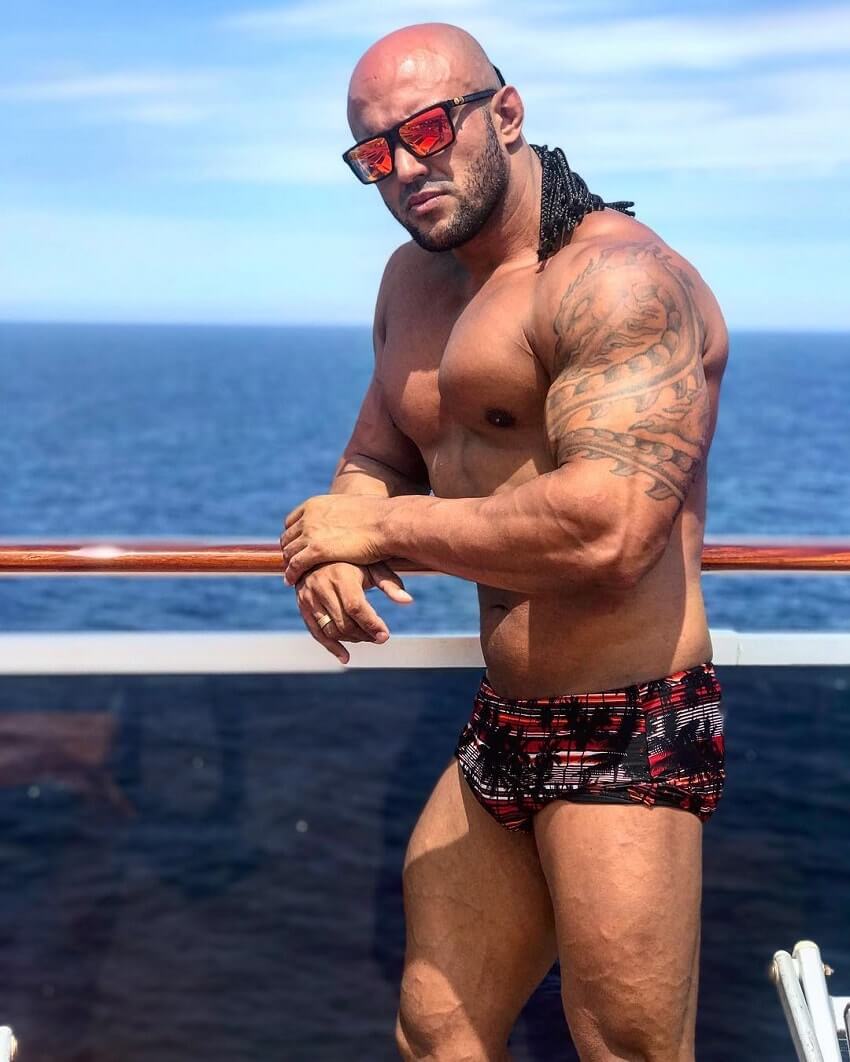 Danilo Franca posing shirtless by the sea, looking huge and ripped