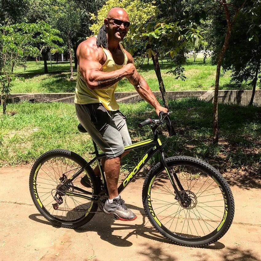 Danilo Franca flexing his arm while riding a bicycle