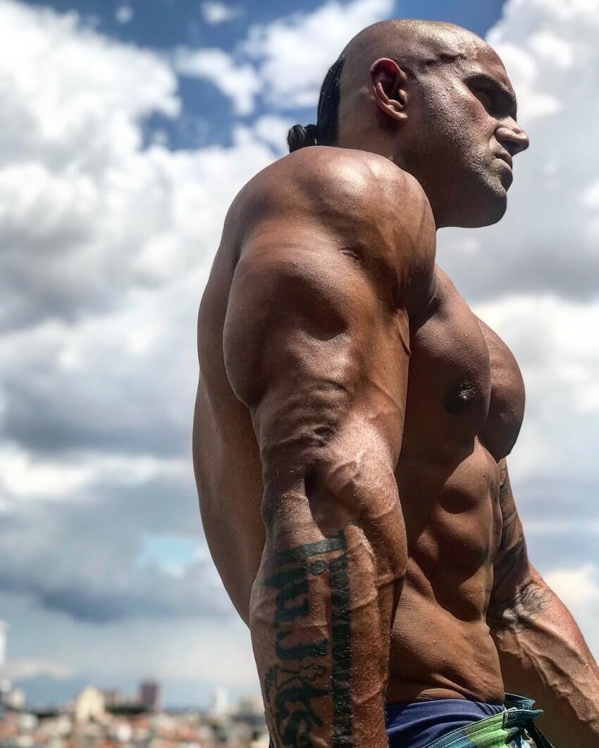 Danilo Franca flexing his ripped and bulging triceps outdoors