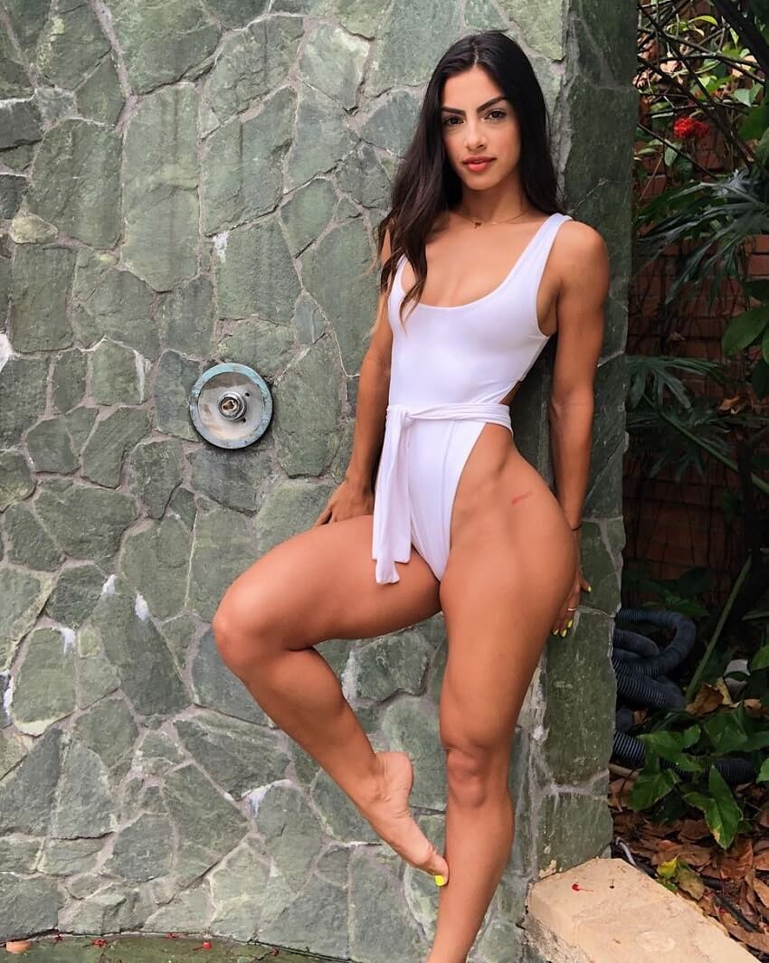 Eva Quiala posing for a photo in a revealing white dress, looking fit and curvy
