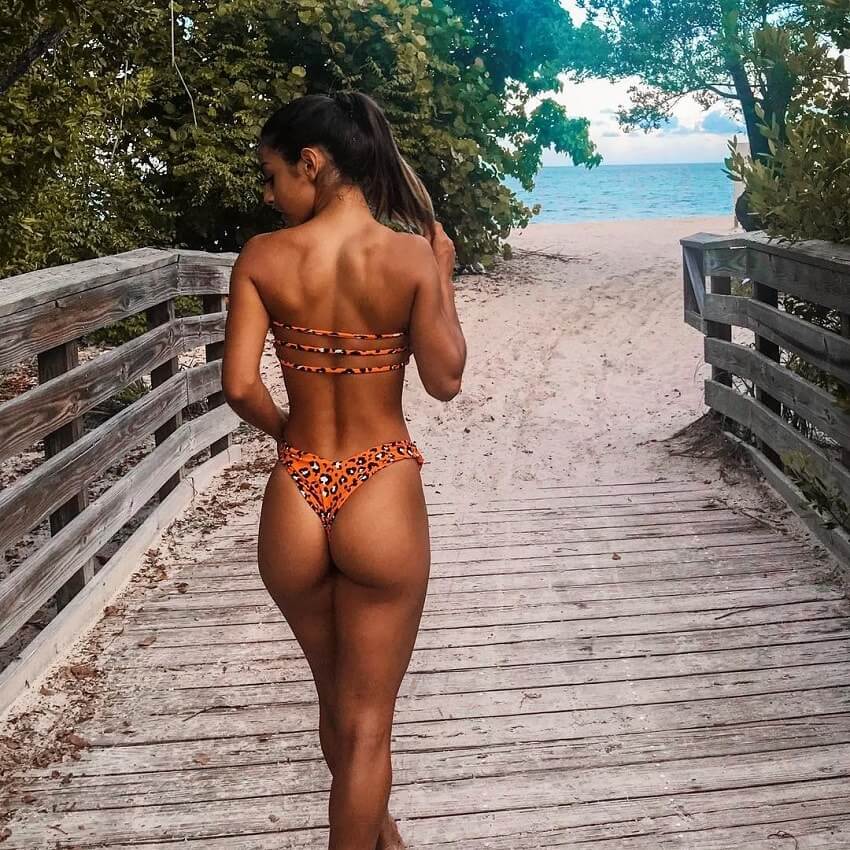 Eva Quiala walking down a wooden pathway to a beach in a bikini