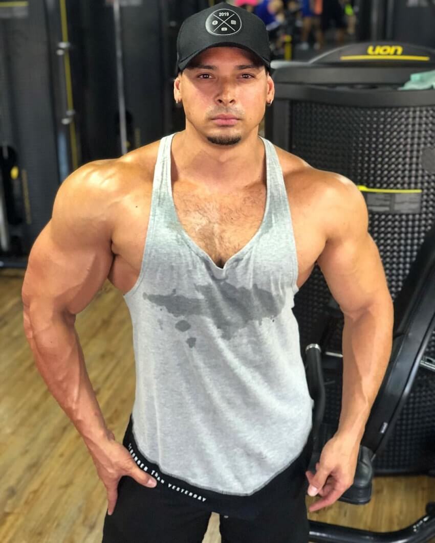 Felipe Franco posing in a grey tank top in the gym