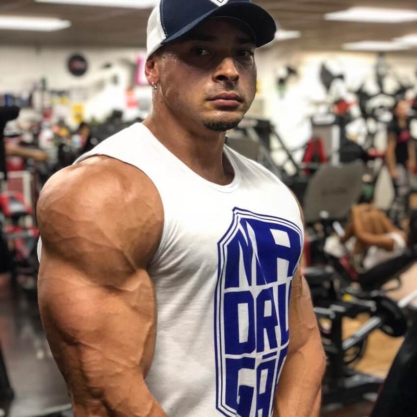 Felipe Franco flexing his huge arms and shoulders in a white tank top