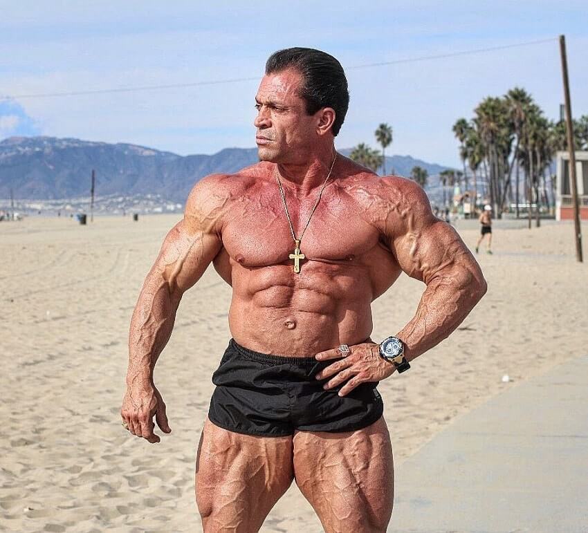 Fernando Sardinha standing shirtless on the beach, looking vascular and ripped