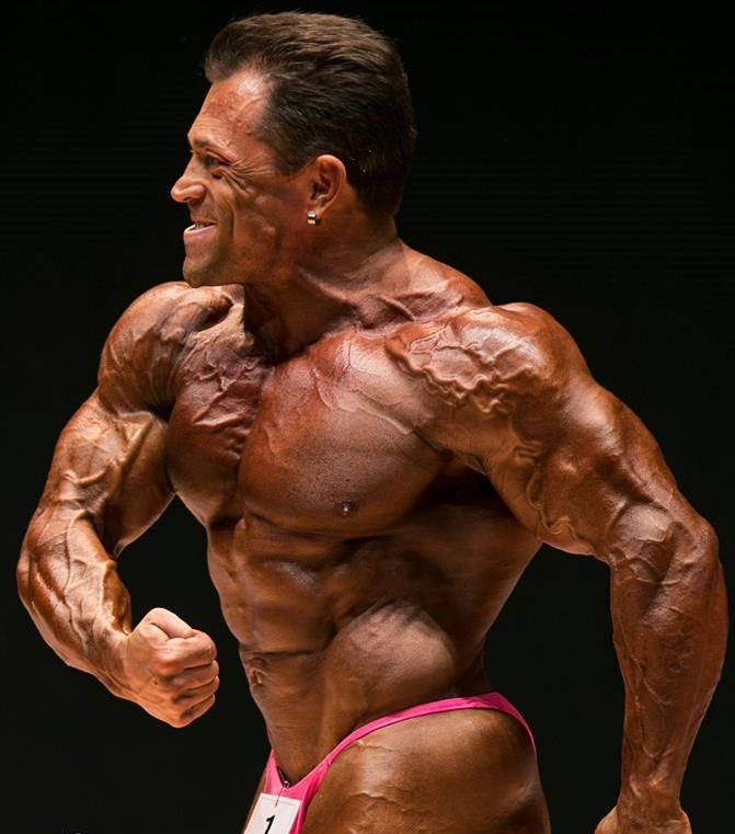 Fernando Sardinha posing side chest on the bodybuilding stage