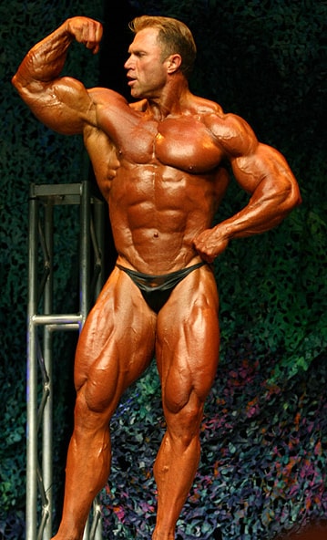 Gary Strydom flexing his biceps in front of an audience in a bodybuilding show