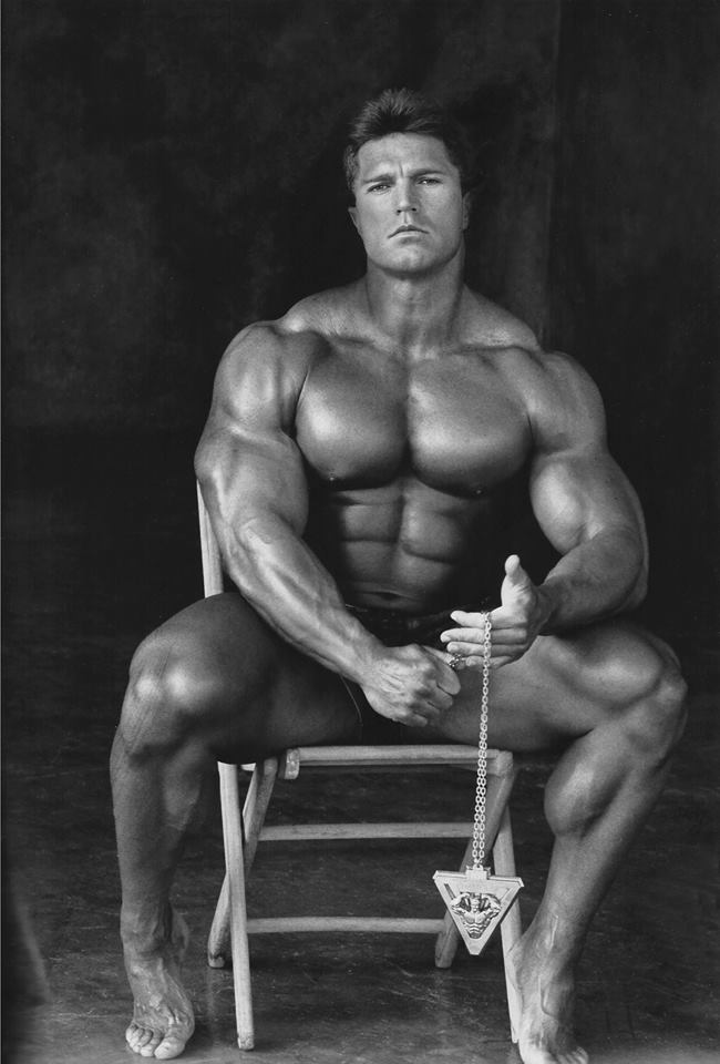 Gary Strydom posing shirtless seated down, looking huge and ripped