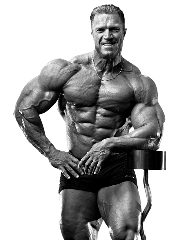 Gary Strydom posing shirtless leaning against a curved barbell in a bodybuilding photo shoot