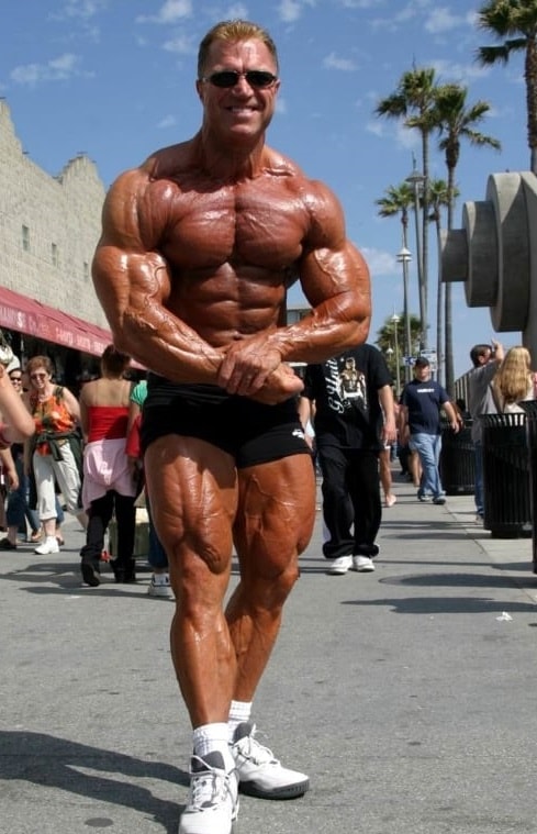 Gary Strydom flexing shirtless on the Venice beach with black sunglasses on