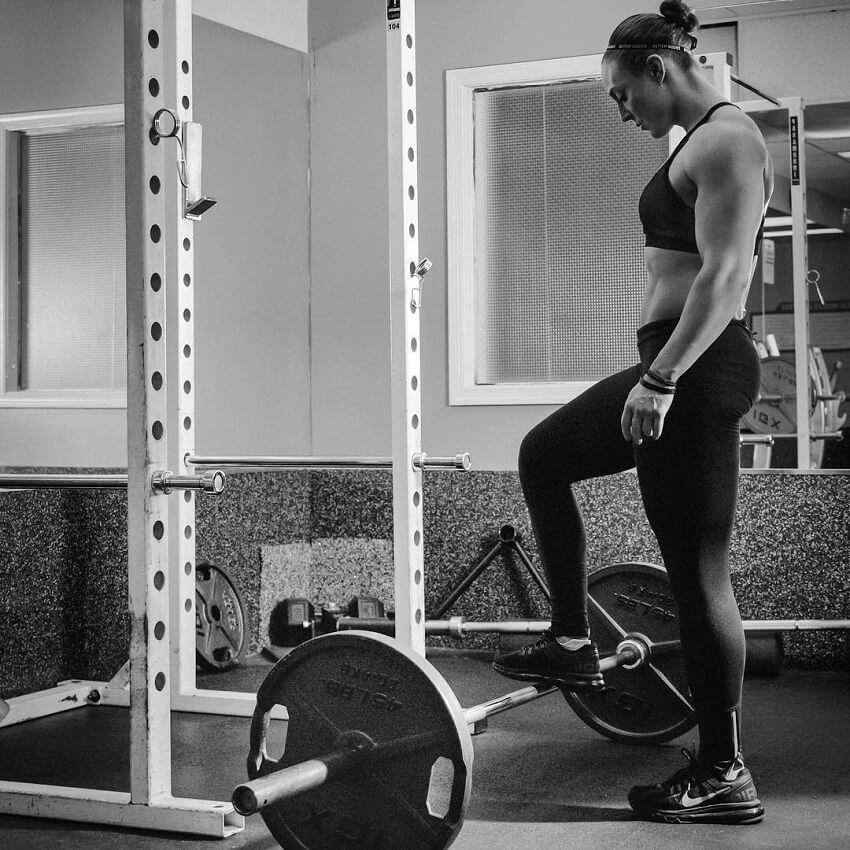 Katie Lee standing by a squat rack in the gym