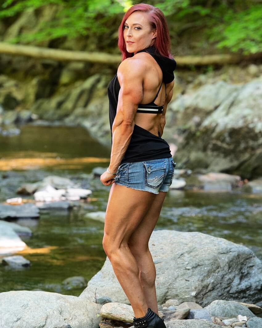 Katie Lee standing by a creek in nature, looking fit and aesthetic