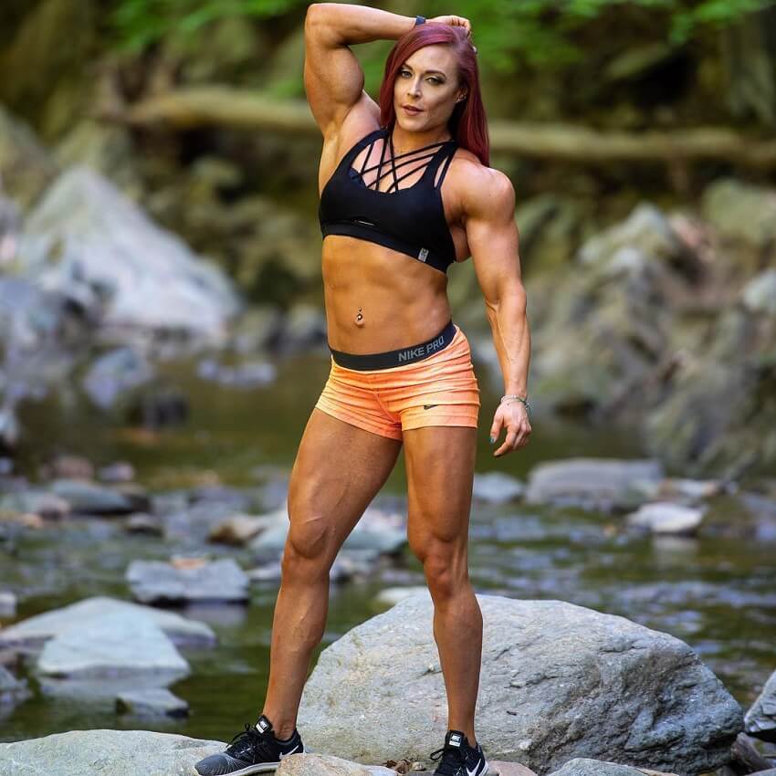 Katie Lee standing on a rock by a creek, looking fit and lean