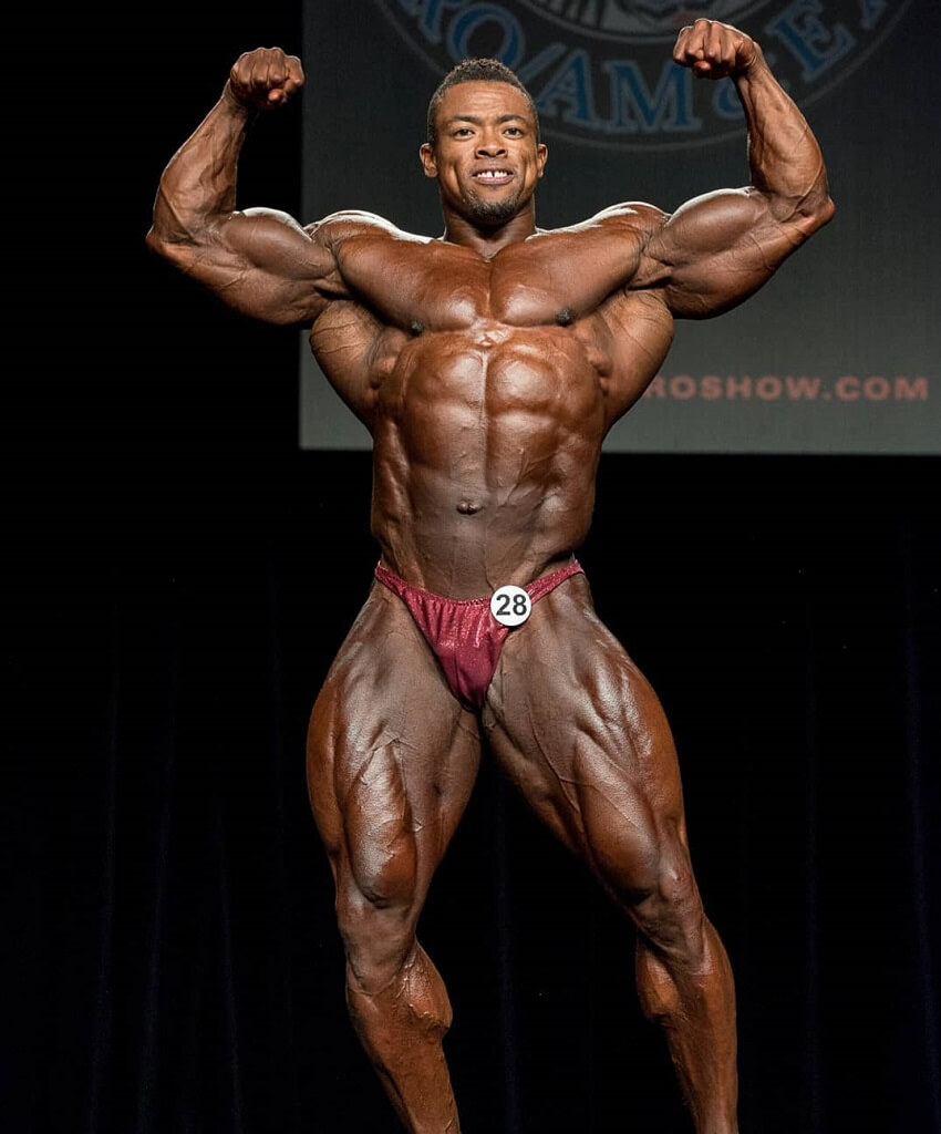 Ricardo Correia hitting a front double biceps pose on the bodybuilding stage