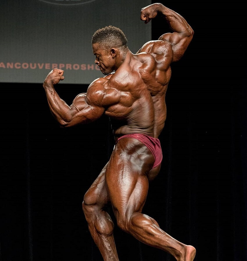 Ricardo Correia performing a pose on a bodybuilding stage, looking