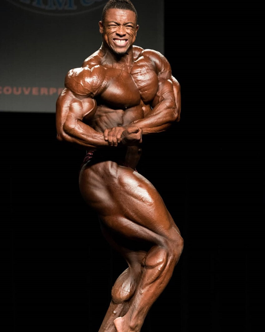 Ricardo Correia hitting a side chest pose on a bodybuilding stage