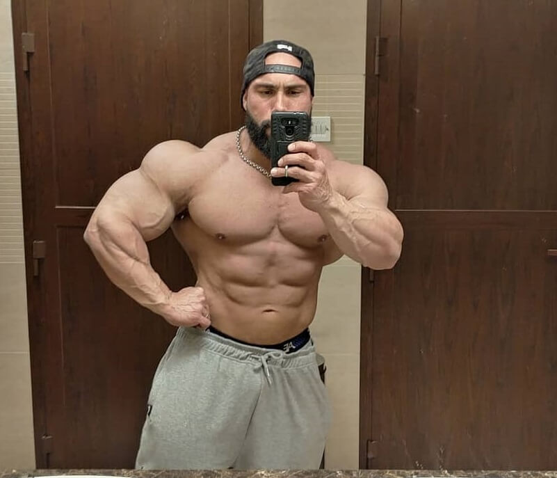 Samir Troudi taking a selfie of his huge and swole muscles in a mirror