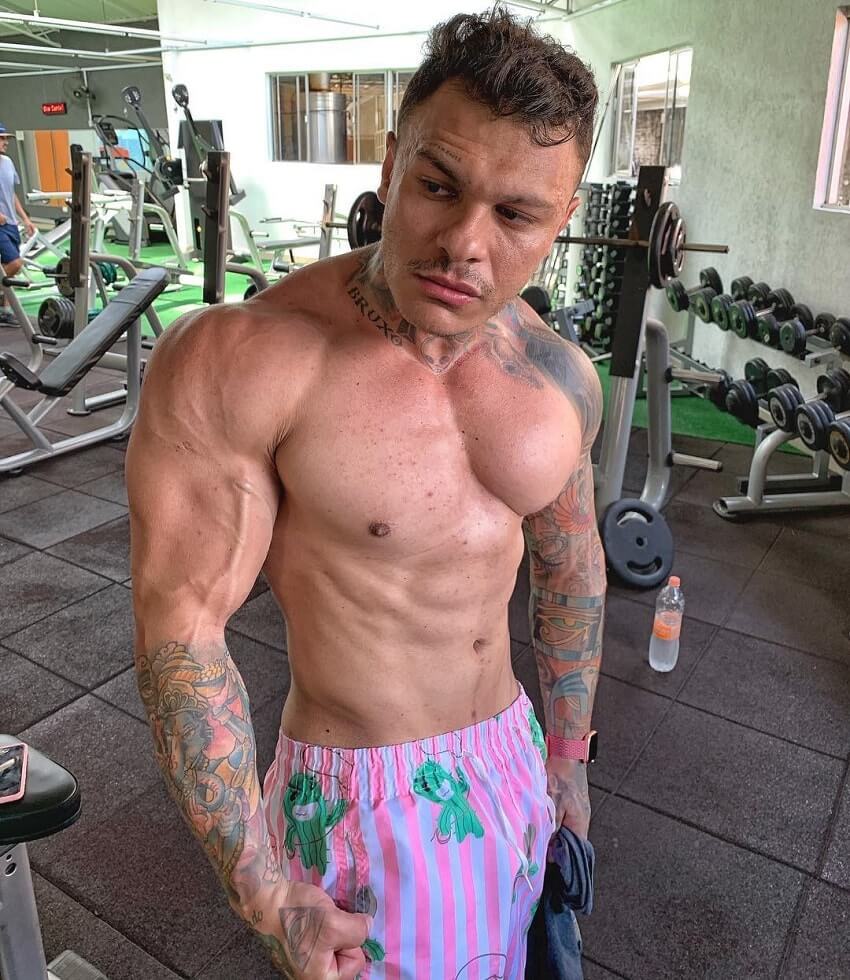 Tiago Toguro posing shirtless in the weight room