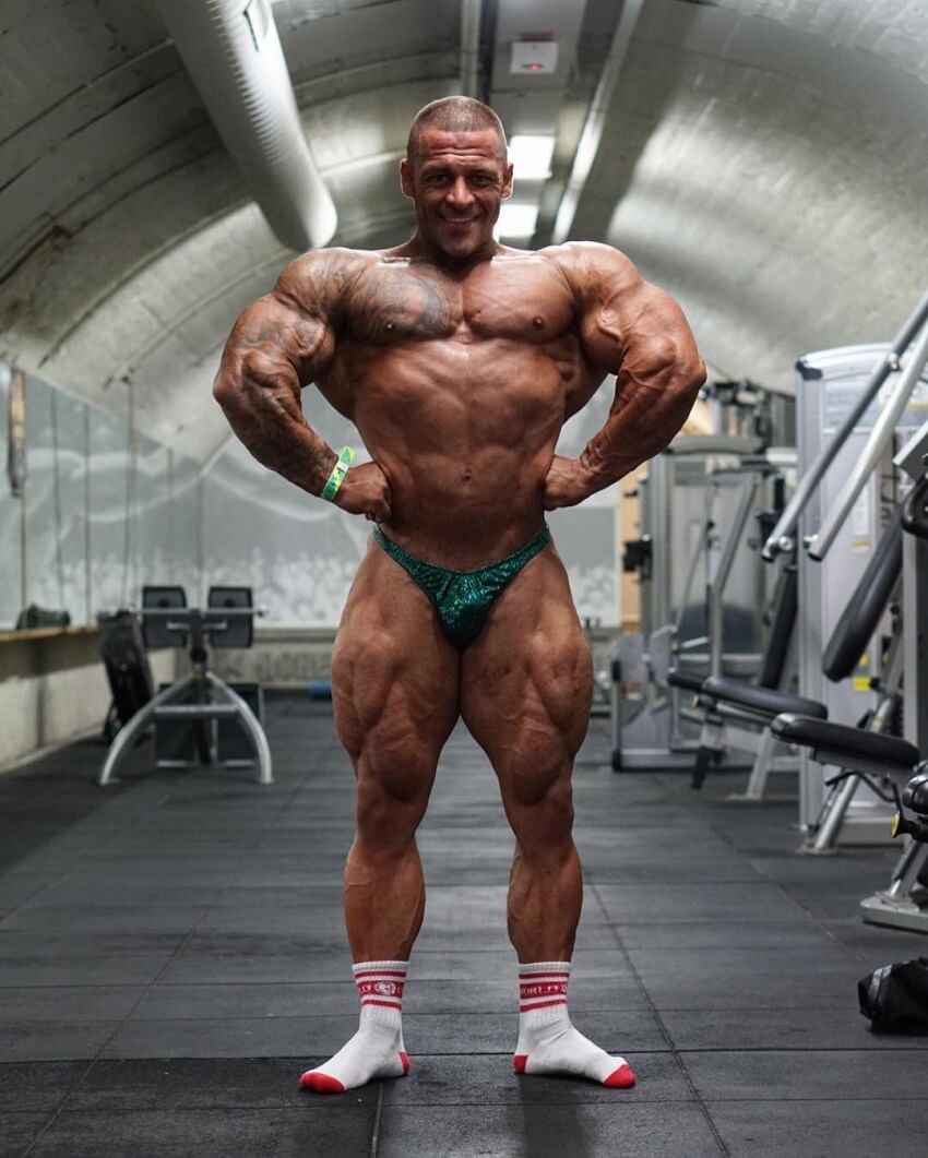 Aaron Polites performing a front lat spread shirtless in the gym