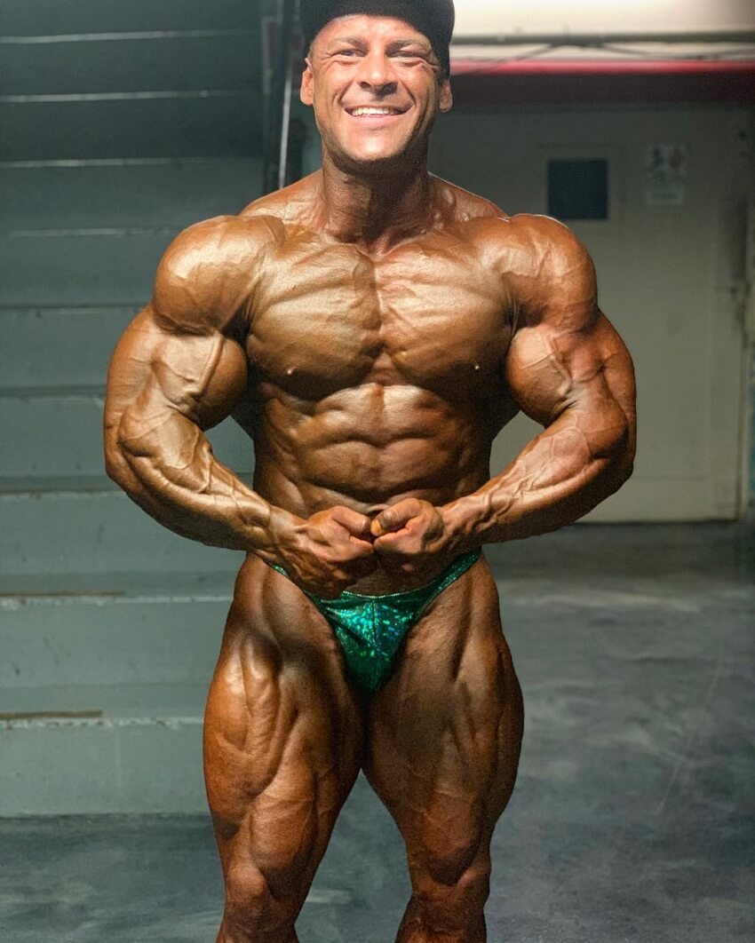 Aaron Polites posing shirtless backstage, looking muscular and ripped