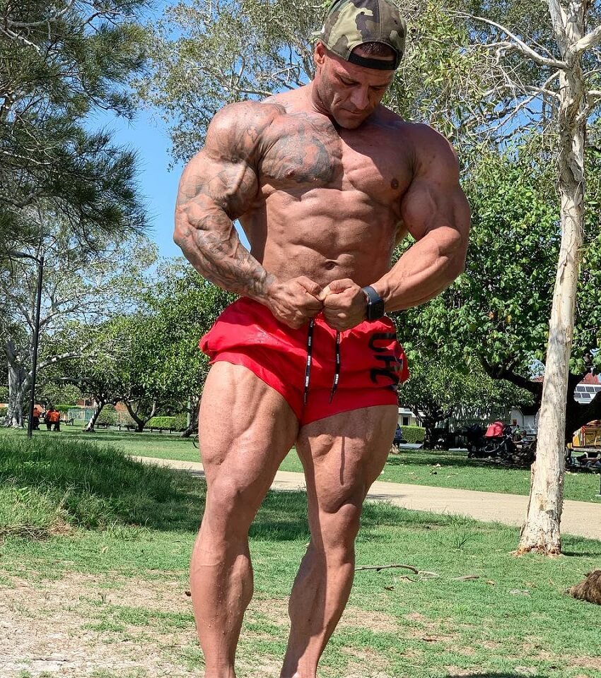 Aaron Polites flexing his shirtless muscles outdoors