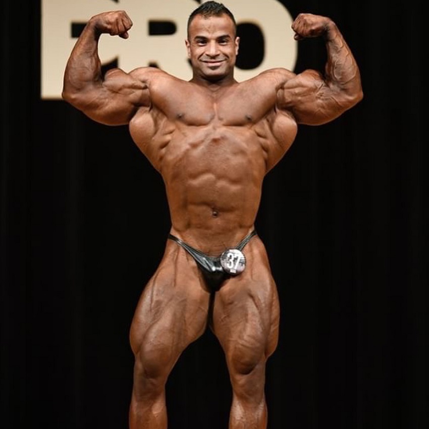 Ahmed Elsadany flexing front double biceps on a bodybuilding stage