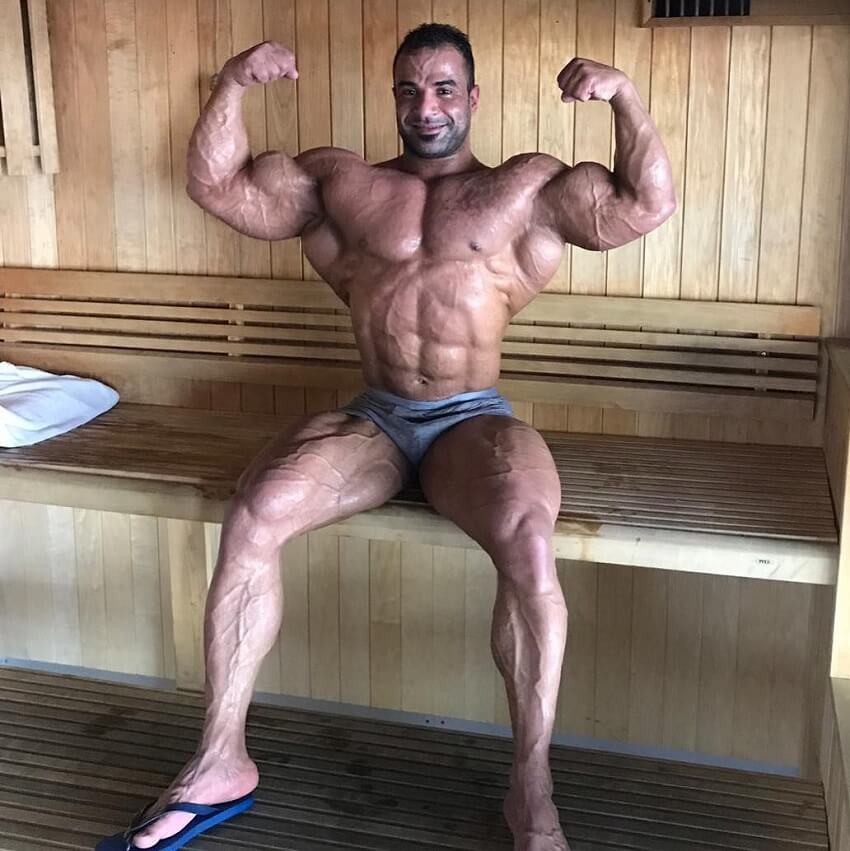 Ahmed Elsadany flexing shirtless in a sauna, looking awesome and ripped