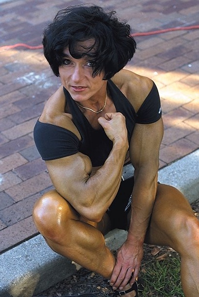 Christa Bauch flexing her arm while sitting outdoors