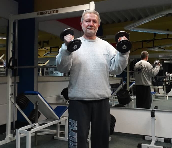 Jusup Wilkosz now, posing with dumbbells in the gym