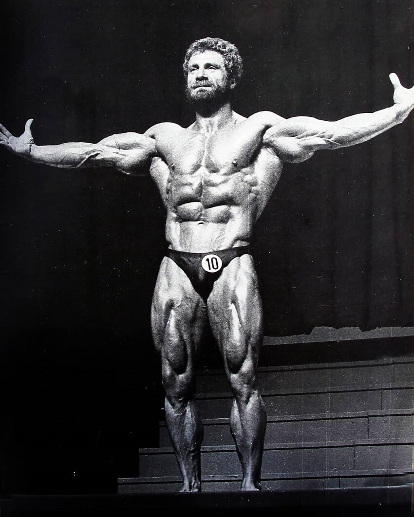 Jusup Wilkosz spreading his arms wide on a bodybuilding stage