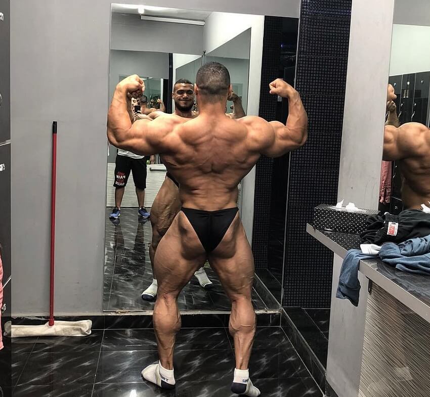 Mohammed Foda practicing back double biceps pose in front of a mirror