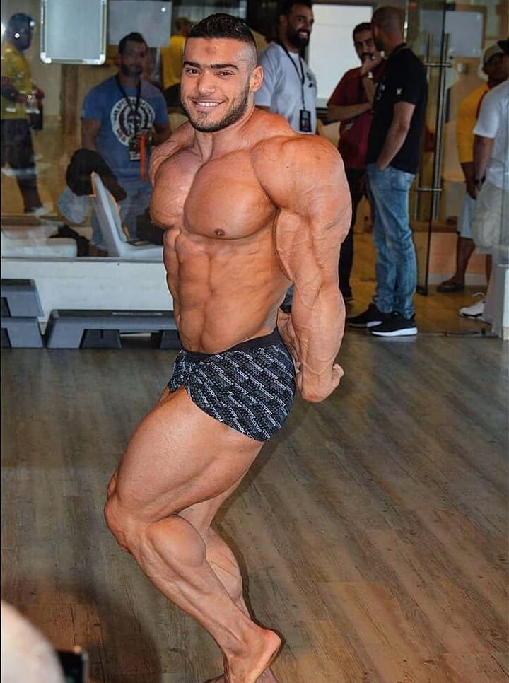 Mohammed Foda doing a shirtless side triceps pose, looking swole and ripped