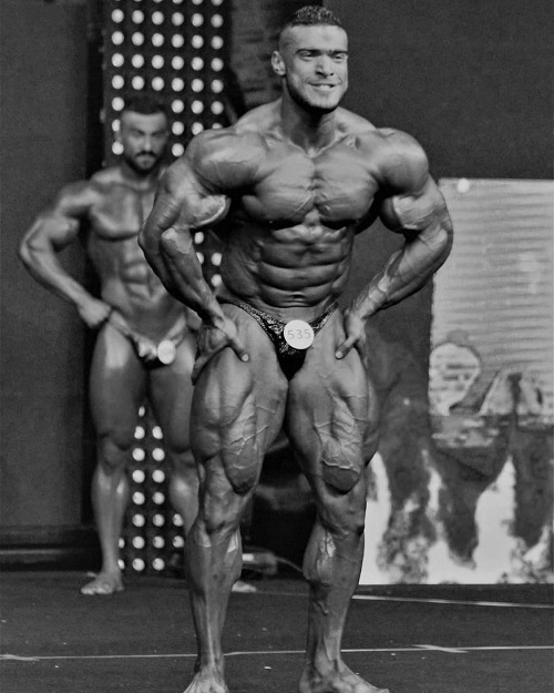 Mohammed Foda posing on a bodybuilding stage looking massive and ripped