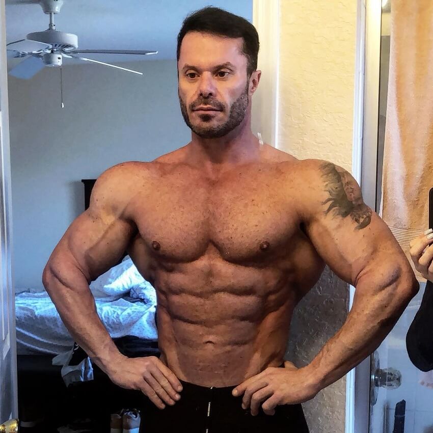 Renato Cariani posing shirtless in his apartment, looking aesthetic and muscular