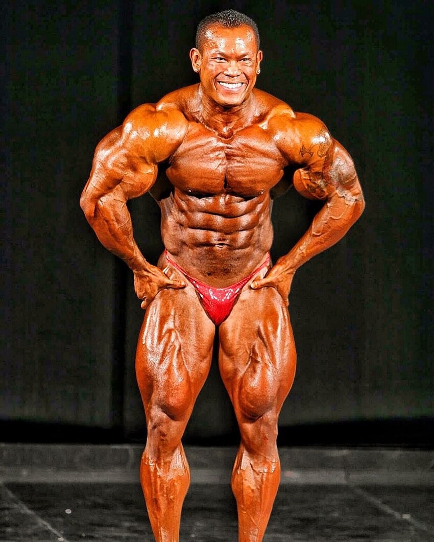 Kris Dim flexing most muscular on a bodybuilding stage