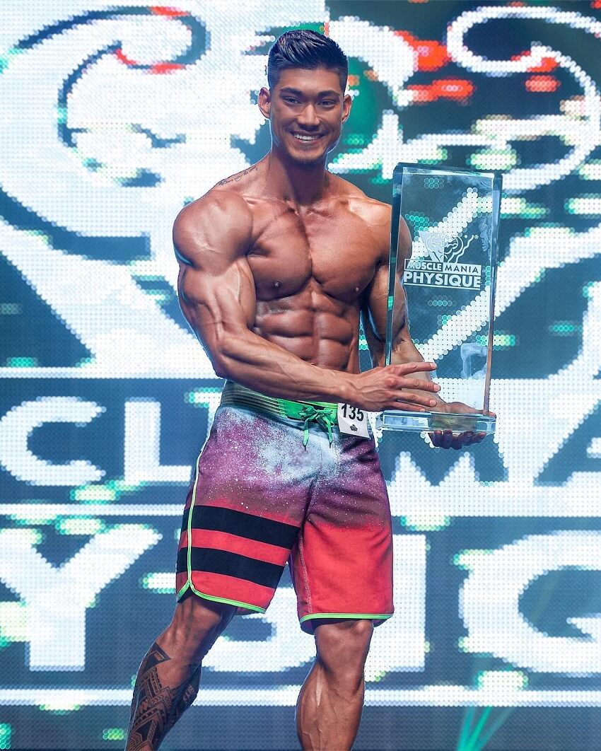 Nicolas Iong posing with a trophy on a bodybuilding stage