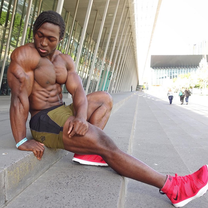 Kwame Duah flexing his triceps shirtless, looking ripped