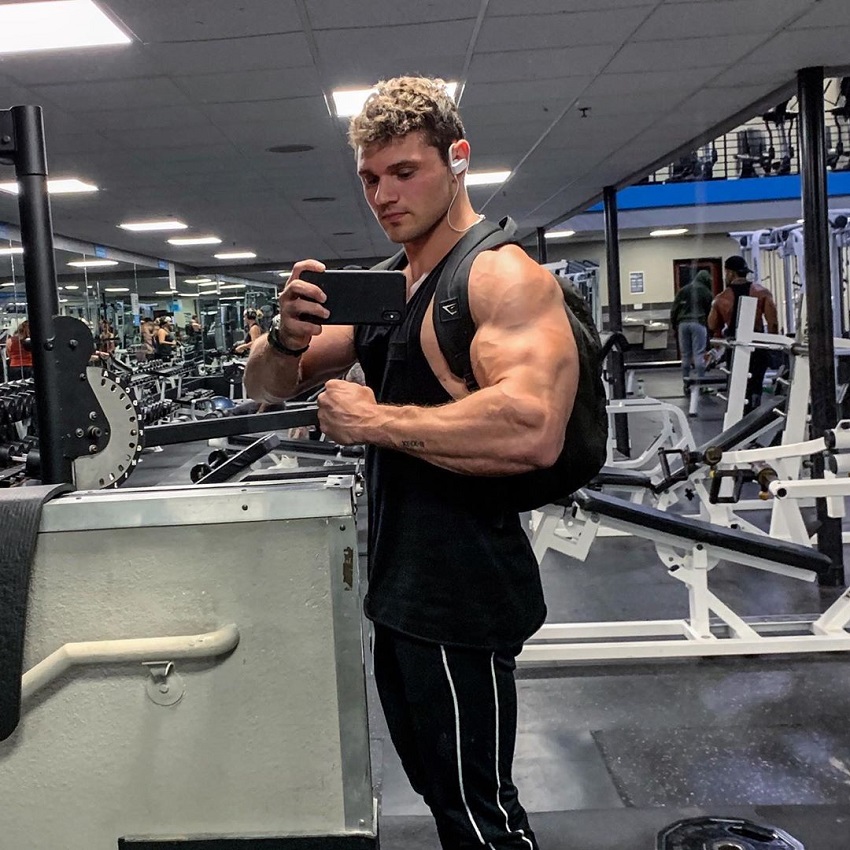 Chris Clark flexing his arms in the gym mirror