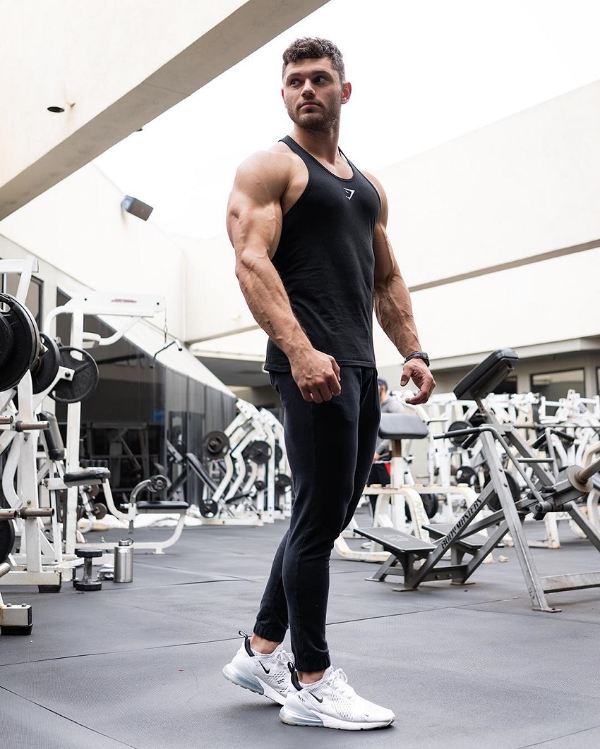 Chris Clark posing in the gym showing off his muscular arms