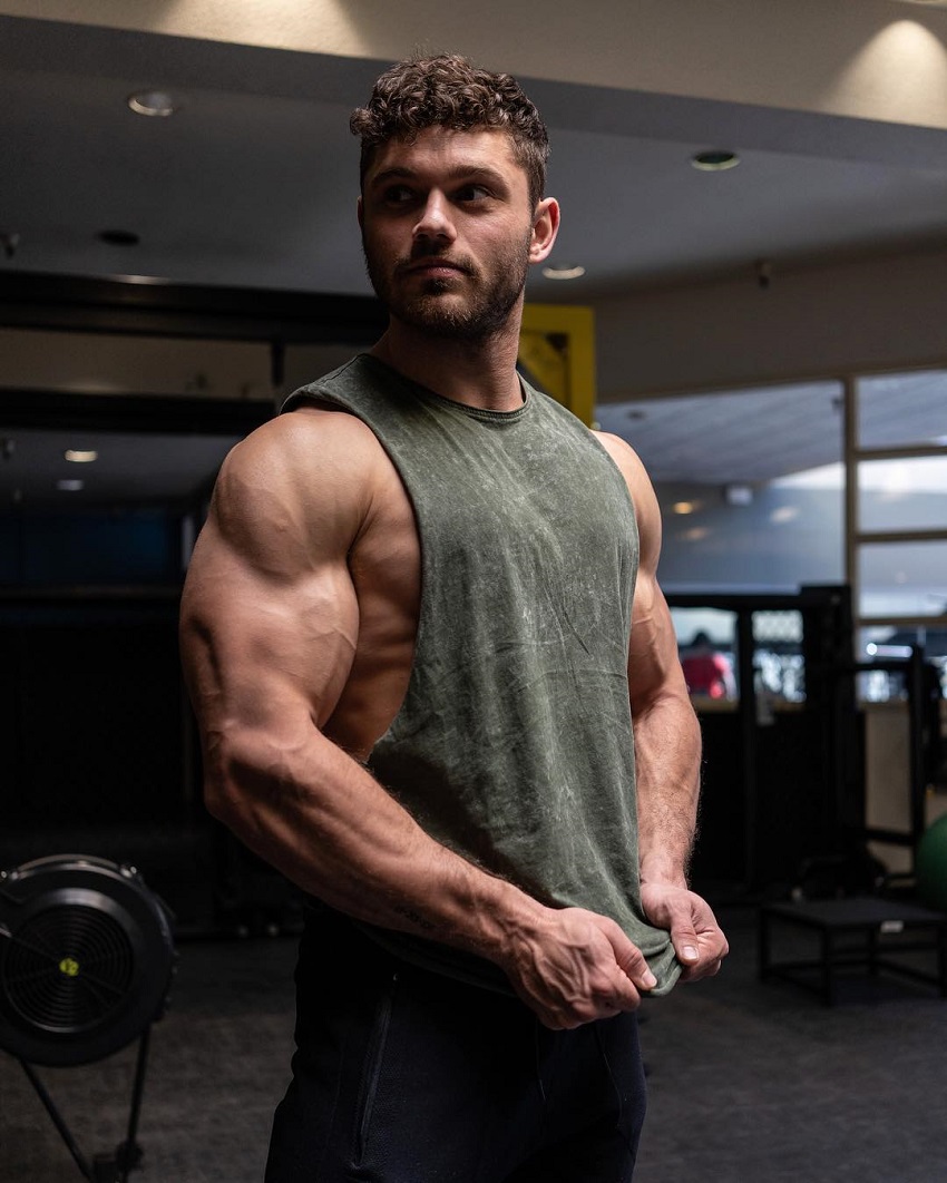 Chris Clark flexing his ripped triceps in a grey tank top