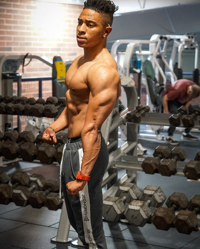 Evan Johnson flexing triceps shirtless in the gym