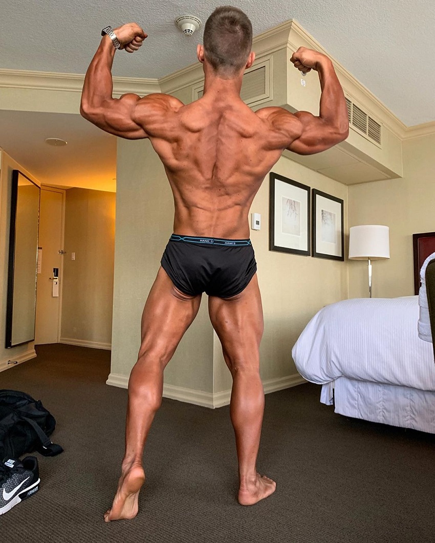 Jordan Strickland flexing back double biceps showing off his ripped back