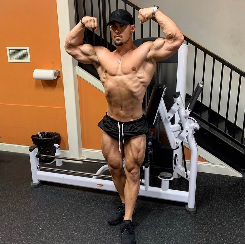 Jordan Strickland performing a front double biceps pose shirtless in the gym