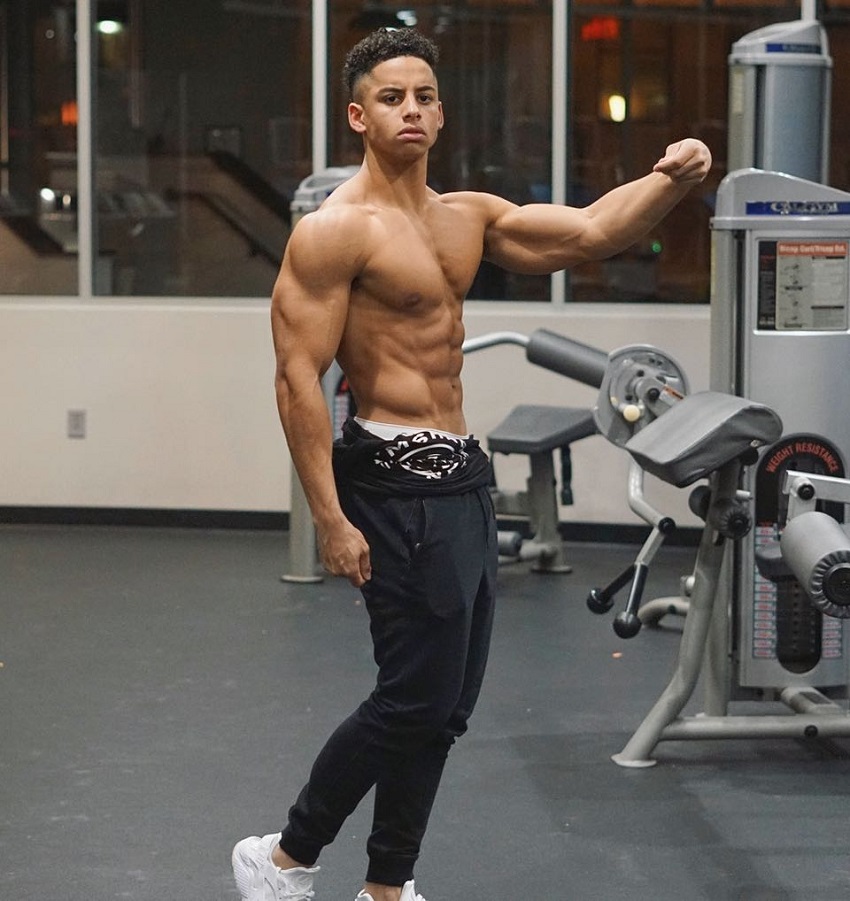 Michael Smith posing shirtless in the gym flexing