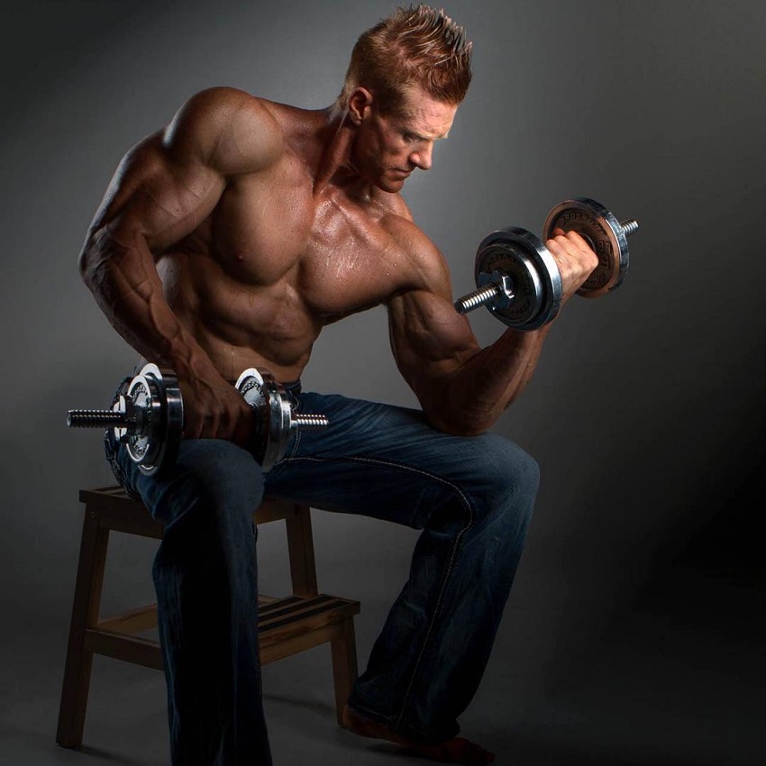 Brandon Budlong training biceps seated on a chair