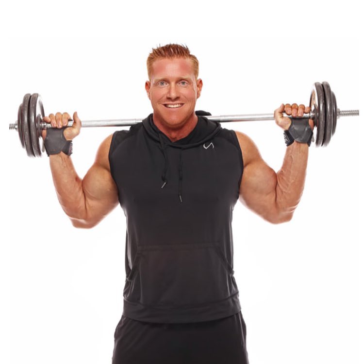 Brandon Budlong posing with a small barbell behind his back