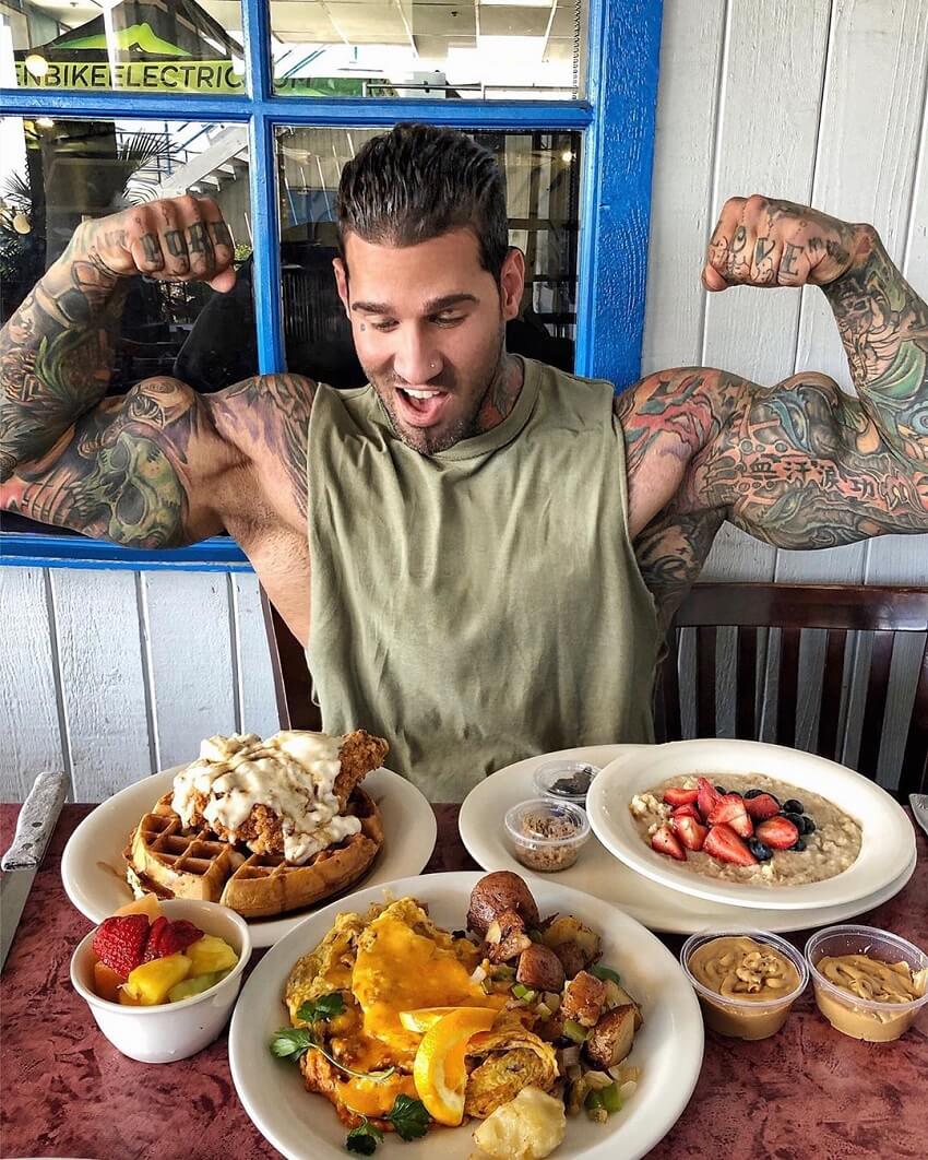 Michael Giovanni Rivera flexing in front of a table full of healthy food