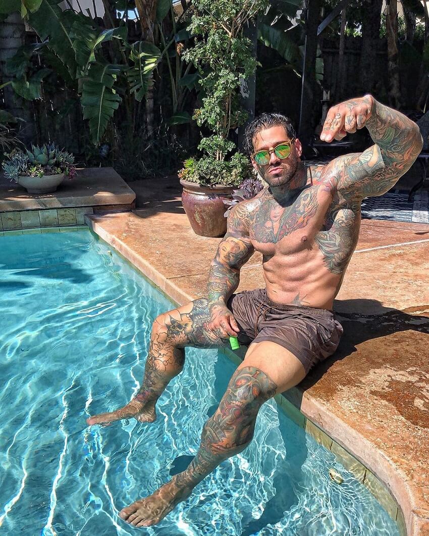 Michael Giovanni Rivera flexing his biceps while sitting by the pool